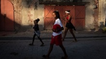 Mädchen gehen bei Sonnenuntergang durch eine Straße in Jacmel. Die Küstenstadt zeigt den Alltag fernab politischer Krisen. Foto: epa/Johnson Sabin