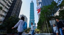Menschen gehen in Taipeh an einer Taiwan-Flagge vorbei, während das Land im Vorfeld der Präsidentschaftswahl im Zeichen politischer Spannung steht. Foto: EPA/Daniel Ceng