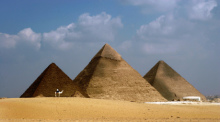 Ein Mann auf einem Kamel reitet vor den Pyramiden von Gizeh (Ägypten) vorbei. Die Pyramiden des Mykerinos (l-r), des Chephren und Cheops. Foto: Mike Nelson/epa/dpa