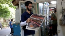 Ein Mann liest in Teheran eine Zeitung mit Bildern von Ali Khameneis Beisetzung und dessen Sohn Mojtaba Khamenei. Foto: Abedin Taherkenareh/epa