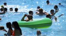 Besucher schwimmen im Wasser im Grugabad in Essen. Foto: Christoph Reichwein/dpa