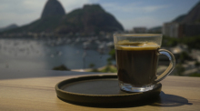 Eine Kaffeetasse steht an der Theke eines Cafés mit Blick auf das Meer und den Zuckerhut. Foto: Andre Borges/dpa
