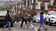 Leute gehen an einer Häuserreihe im Norden Londons vorbei. Archivfoto: epa/TOLGA AKMEN