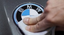 Ein Angestellter reinigt auf der Internationalen Automobilausstellung (IAA) in München ein BMW-Logo auf einem Auto. Foto: epa/Ronald Witteklogo Auf Einem Auto.