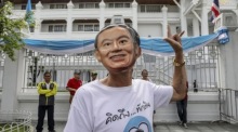 Ein Anhänger des ehemaligen thailändischen Premierministers Thaksin Shinawatra trägt eine Maske, die Shinawatra darstellt. Foto: epa/Narong Sangnak