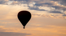 Ein Heißluftballon fährt am frühen Morgen vor dem leicht bewölkten Himmel über den Feldern und Wiesen in der Wesermarsch. Foto: Hauke-Christian Dittrich/dpa