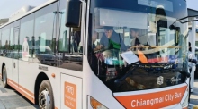 Ein einsamer blauer Stadtbus fährt durch eine belebte Straße in Chiang Mai, vorbei an wartenden Fahrgästen am Straßenrand. Foto: Prachachat