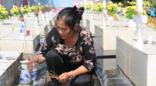 Nguyen Thi Nhiem zündet Räucherstäbchen auf einem Friedhof an und betet für die Seelen der ungeborenen Kinder. Foto: Bac Pham/dpa