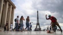 Ein Händler von Eiffelturm-Souvenirs erklärt einer Frau auf dem Trocadero-Platz in Paris, wie man ein Foto mit dem Eiffelturm macht. Foto: epa/Mohammed Badra