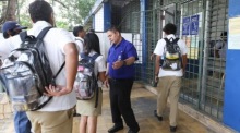 Ein Schulmitarbeiter überprüft Schüler am Eingang des Albert-Camus-Instituts in San Salvador nach neuen Disziplin- und Ordnungsregeln. Foto: epa/Javier Aparicio