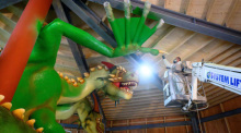 Ein Lackierer arbeitet an einem dreiköpfigen Drachen auf dem Bocksberg im Harz. Der Drache wird als Teil einer neuen Sommerrodelbahn montiert. Die Attraktion soll 2025 fertiggestellt sein. Foto: Swen Pförtner/dpa