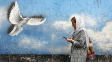 Eine Frau aus dem Iran geht an einem Wandgemälde mit einem Friedensvogel in einer Straße in der Innenstadt vorbei. Foto: epa/Abedin Taherkenareh