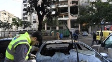 Mitglieder des Zivilschutzes inspizieren ein Fahrzeug, das in der Nähe des von einem Drohnenangriff getroffenen Gebäudes in einem südlichen Vorort von Beirut beschädigt wurde. Foto: epa/Stringer