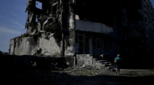 Eine Frau geht an einem durch russischen Beschuss zerstörten Gebäude in Borodjanka am Stadtrand von Kiew vorbei. Foto: Natacha Pisarenko