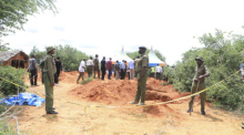 Polizeibeamte stehen neben einer Absperrung vor Gräbern, aus denen die Polizei die Leichen von Opfern eines christlichen Sektenkults exhumiert. Foto: Uncredited/Ap/dpa