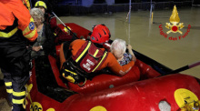 Feuerwehrleute helfen älteren Frauen aus einem Schlauchboot, die sie aus ihren Häusern gerettet haben. Foto: Vigili del Fuoco/dpa