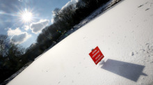 Auf der zugefrorenen Eisfläche eines Teiches im Grugapark ist ein Schild mit der Aufschrift "Achtung Lebensgefahr! Eisfläche nicht betreten" aufgestellt worden. Foto: Roland Weihrauch/dpa