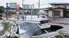 Ein Auto steckt auf einer eingestürzten Straße fest, nachdem ein starkes Beben den Nordosten Japans erschüttert und Schäden verursacht hat. Foto: EPA/Jiji Press