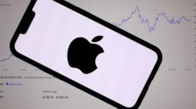 Das Apple-Logo vor einem Börsenchart auf einem Laptop. KI- und Technologiekonzerne stehen im Fokus der Finanzmärkte. Foto: EPA/Adam Vaughan