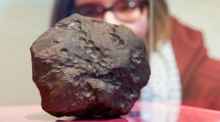 Eine Besucherin betrachtet die strukturierte Oberfläche des "Meteorit Elmshorn" während der Pressekonferenz im Museum der Natur Hamburg. Foto: Ulrich Perrey/dpa