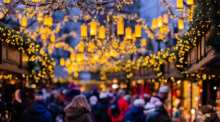 Besucher gehen über den Weihnachtsmarkt am Alter Markt. Viele Städte prüfen, wie sie bei der Weihnachtsbeleuchtung Energie sparen können. Foto: Rolf Vennenbernd/dpa