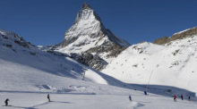 Skifahrer fahren die Pisten am Riffelberg mit dem Matterhorn im Hintergrund hinunter. Foto: Jean-Christophe Bott/Keystone/dpa
