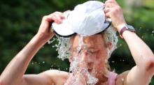 Eine Teilnehmerin des Hamburger Halbmarathons kühlt sich an einer Erfrischungsstation mit Wasser gegen die sommerliche Hitze ab. Foto: dpa/Markus Tischler