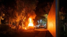 Ein Polizeifahrzeug brennt bei Ausschreitungen vor einem Krankenhaus in Alice Springs nach Festnahme eines Verdächtigen im Fall eines getöteten Kindes. Foto: EPA/Rhett Hammerton