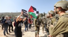 FriedensaktivistInnen stehen vor israelischen Soldaten am Eingang der Westbankstadt Hawara. Foto: epa/Alaa Badarneh