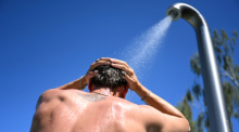 Ein Mann steht im Sommerbad Humboldthain unter der Dusche. Derzeit rollt eine Hitzewelle über Brandenburg und Berlin. Foto: Elisa Schu/dpa