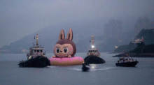 Eine große aufblasbare Labubu-Figur wird von einem Schleppboot gezogen. Foto: Vernon Yuen/Nexpher Via Zuma Press Wire/dpa