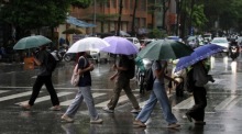 Menschen mit Regenschirmen gehen durch den Regen in Hanoi nach dem Eintreffen des Taifuns Bualoi. Mehrere Tote und Vermisste. Foto: epa/Luong Thai Linh