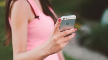 Eine Frau in einem pinken Top hält ein Smartphone in der Hand, eine Darstellung der mobilen Vernetzung in der heutigen Gesellschaft. Foto: Pixabay/Jan Vašek