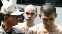 Die mutmaßlichen Erawan-Anschlagsverdächtigen Yusufu Mieraili (r.) und Adem Karadag (M.) werden von Polizisten und Justizvollzugsbeamten eskortiert. Foto: epa/Narong Sangnak