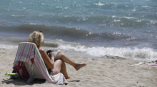 Eine Frau sonnt sich am Strand von Arenal. Auf Mallorca scheint es fast so, als hätte es nie einen Corona-Stillstand gegeben. Foto: Clara Margais/dpa