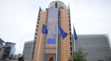EU-Fahnen flattern im Wind, während Fußgänger am EU-Hauptsitz vorbeigehen. Foto: Virginia Mayo/Ap/dpa