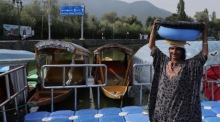 Eine Fischerin trägt einen Eimer mit frischem Fang am Dal-See in Srinagar und zeigt den Alltag der Menschen in Kaschmir. Foto: EPA/Farooq Khan