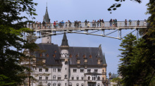 Touristen stehen auf der Marienbrücke vor dem Schloss Neuschwanstein. Foto: Karl-Josef Hildenbrand/dpa