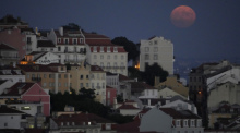Der Vollmond geht hinter dem Stadtteil Castelo auf. (zu dpa: «Kleinkinder in Portugal mutmaßlich von Eltern ausgesetzt») Foto: Armando Franca/Ap/dpa