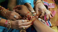 Eine Frau bindet ihrem Bruder während des Raksha-Bandhan-Festes einen heiligen Faden, "Rakhi" genannt, ums Handgelenk. Foto: Jagadeesh Nv