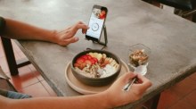 Ein Gast fotografiert im Restaurant seine Frühstücksbowl mit dem Smartphone – Benimmfragen in der modernen Gastronomie. Foto: Unsplash/Evelyn Verdin