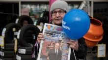 Die Frau hält eine Zeitung mit einem Foto des russischen Präsidenten Wladimir Putin. Foto: epa/Stringer