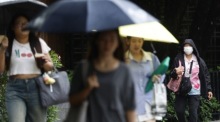 Passanten schützen sich in Bangkok mit Regenschirmen vor einem Regenschauer. Foto: epa/Narong Sangnak