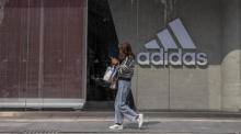 Ein Frau geht an einem Adidas-Geschäft in einem Einkaufsviertel von Sanlitun in Peking vorbei. Foto: epa/Roman Pilipey