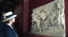 Eine Journalistin betrachtet ein antikes Relief mit der Darstellung von Gladiatorenkämpfen zwischen Gladiatoren und Raubkatzen in der Ausstellung «Sangue e Arena» (Blut und Arena) im Kolosseum. Foto: Del Castillo/Ansa/epa/dpa