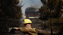 Ein Feuerwehrmann gestikuliert vor einem brennenden Haus während eines Großbrandes in der Vorstadt Voula, südlich von Athen. Foto: epa/Yannis Kolesidis
