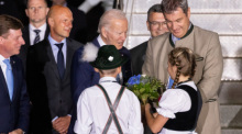Die Kinder Daniela Hauser und Marco Keller begrüßen Joe Biden (M), Präsident der USA, mit einem Blumenstrauß bei seiner Ankunft am Flughafen München. Daneben steht Markus Söder (r, CSU), Ministerpräsident von Bayern. D... Foto: Daniel Karmann/dpa
