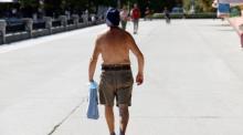 Ein Passant spaziert ohne Hemd durch den Retiro-Park in Madrid. Foto: epa/Chema Moya
