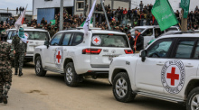 Fahrzeuge des Internationalen Roten Kreuzes stehen bereit, während Kämpfer der Hamas Geiseln an Vertreter des IKRK übergeben. Foto: Abed Rahim Khatib/dpa