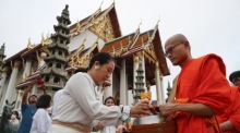 Am frühen Morgen nehmen Buddhisten am Almosengang der Mönche Teil und werden gesegnet. Foto: epa/Rungroj Yongrit